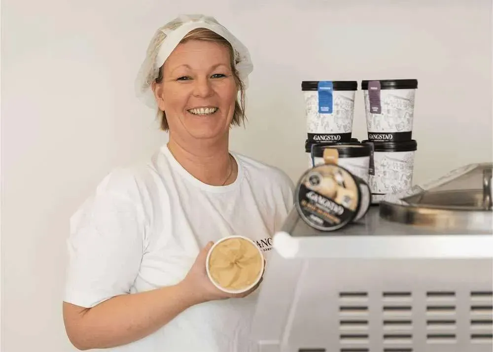 A smiling person next to packages of ice cream
